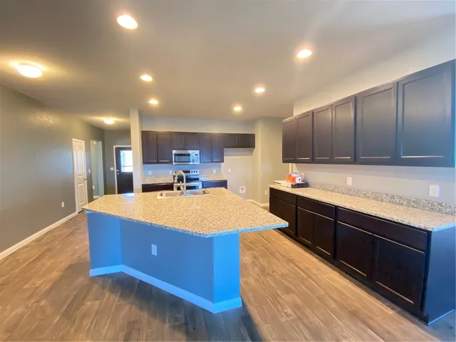 a large kitchen with kitchen island a sink dishwasher a stove and a refrigerator with wooden floor