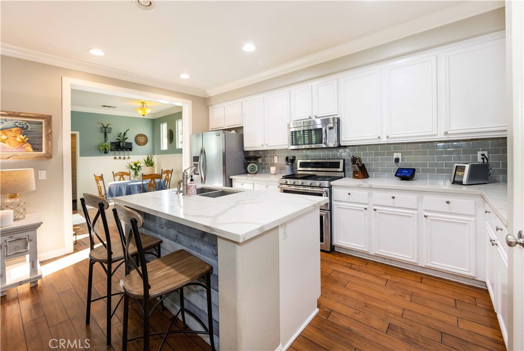 40232 Pasadena Drive Temecula, CA 92591 - Photo 11 of 44 a kitchen with stainless steel appliances kitchen island granite countertop a table chairs sink and cabinets