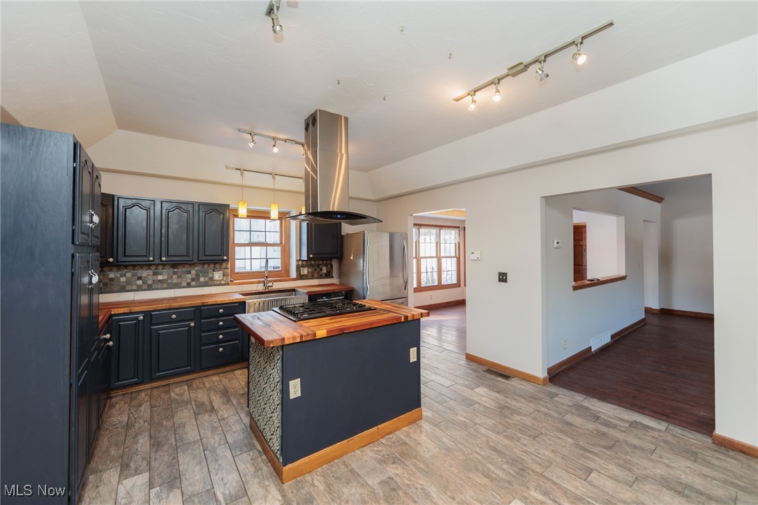 8124 Hartman Road Wadsworth, OH 44281 - Photo 33 of 50 Kitchen featuring island exhaust hood, appliances with stainless steel finishes, vaulted ceiling, a kitchen island, and butcher block counters
