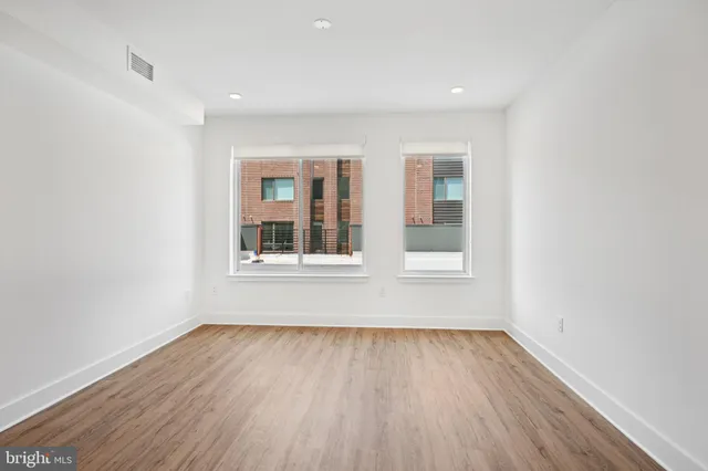 an empty room with wooden floor and windows