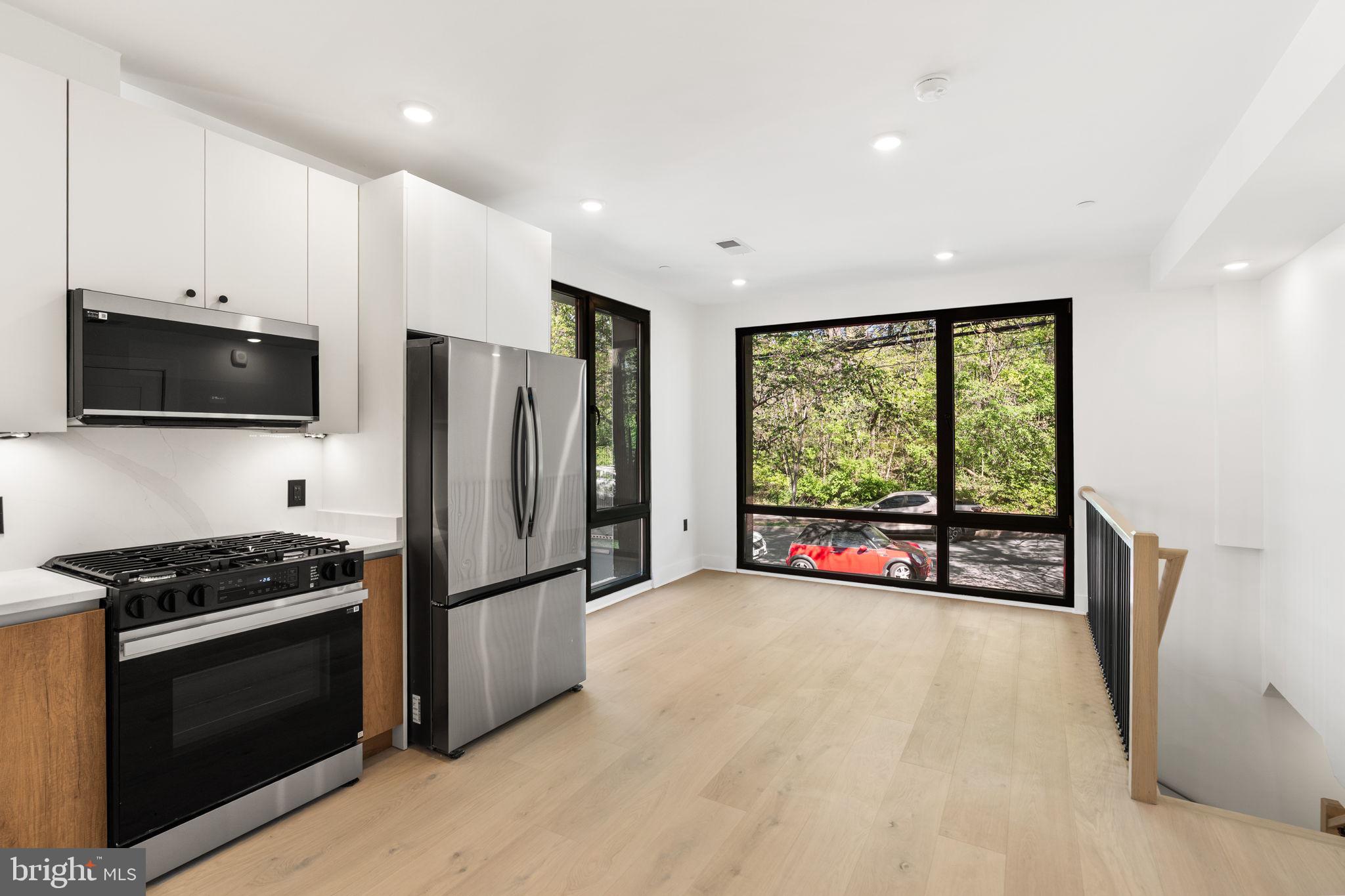 2504 41st Street Northwest, Unit 6 Washington, DC 20007 - Photo 4 of 13 a kitchen with stainless steel appliances a stove top oven a refrigerator and a view of living room