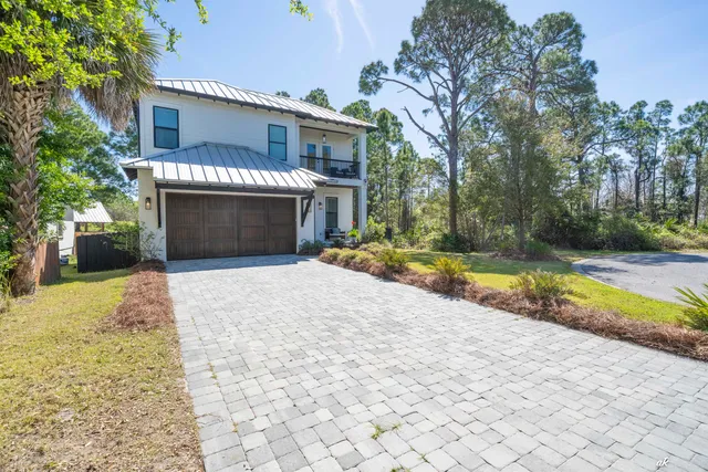 a front view of a house with a yard and potted plants