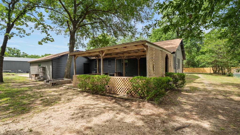 129 King Arthur Road Mabank, TX 75156 - Photo 6 of 33 The property features a covered porch with lattice screening, set against a backdrop of mature trees
