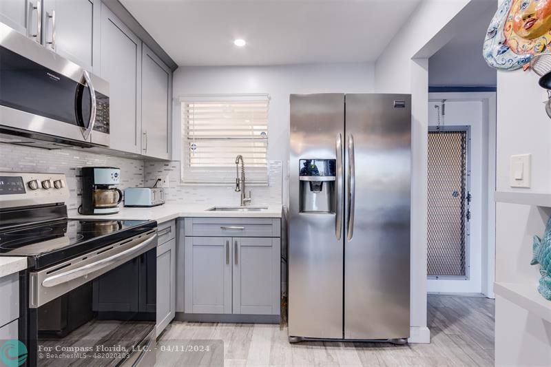 a kitchen with stainless steel appliances granite countertop a refrigerator a sink and white cabinets