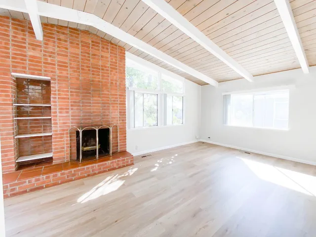 an empty room with windows and fireplace