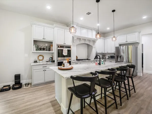 a kitchen with granite countertop a stove a sink a dining table and chairs