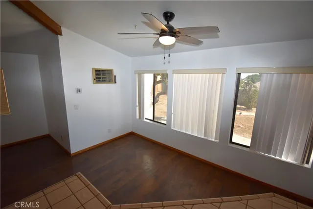 an empty room with windows and ceiling fan
