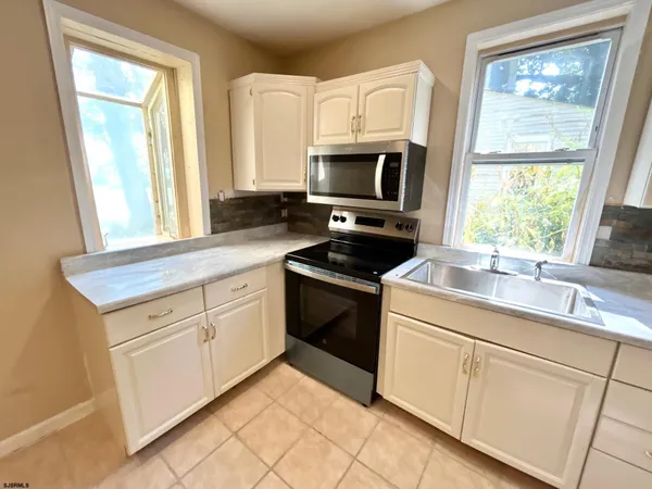 a kitchen with stainless steel appliances granite countertop white cabinets a sink and a window