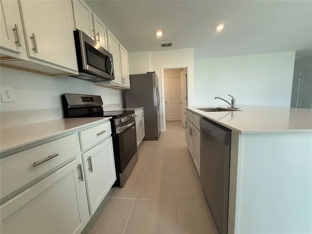 a kitchen with stainless steel appliances granite countertop a sink stove microwave refrigerator and cabinets