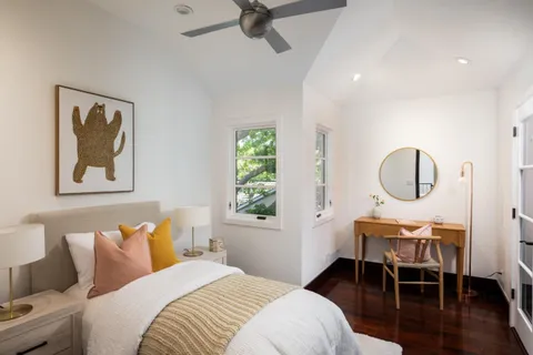 a bedroom with a bed a desk and chair with wooden floor