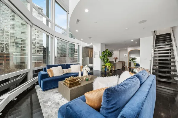 a living room with furniture floor to ceiling window and wooden floor