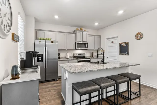 a kitchen with stainless steel appliances granite countertop a refrigerator a sink a stove a microwave and chairs