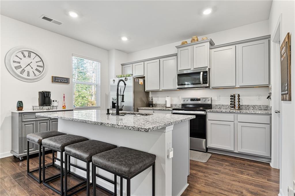 104 Waratah Drive Locust Grove, GA 30248 - Photo 8 of 27 a kitchen with stainless steel appliances granite countertop a stove a sink dishwasher a microwave oven and a refrigerator with wooden floor