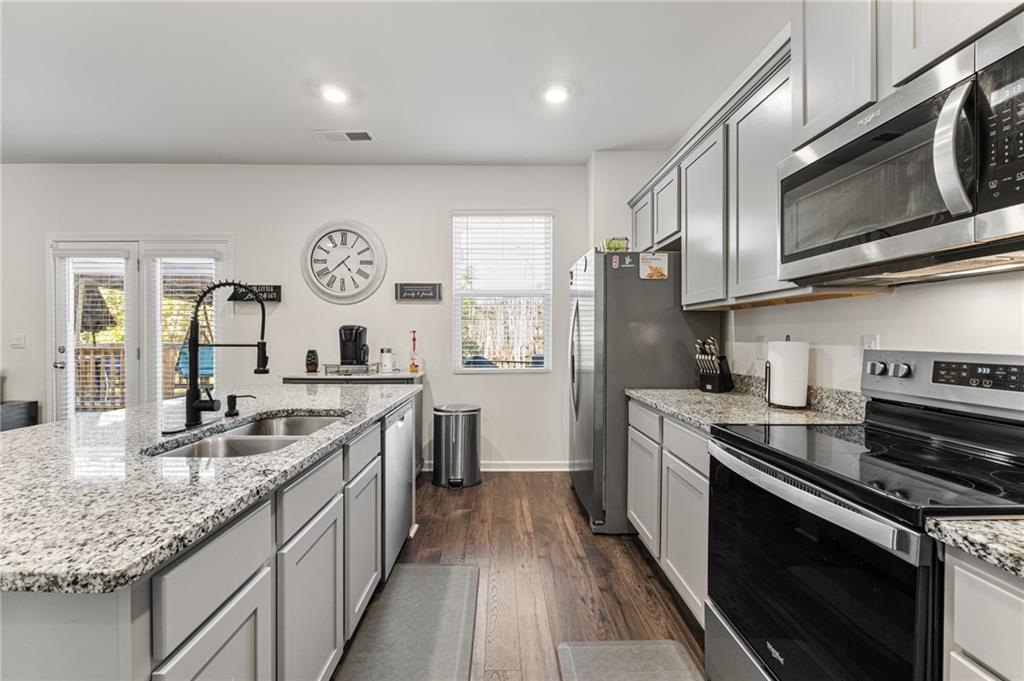 104 Waratah Drive Locust Grove, GA 30248 - Photo 9 of 27 a kitchen with stainless steel appliances granite countertop a stove top oven a sink dishwasher a refrigerator and a oven with wooden floor