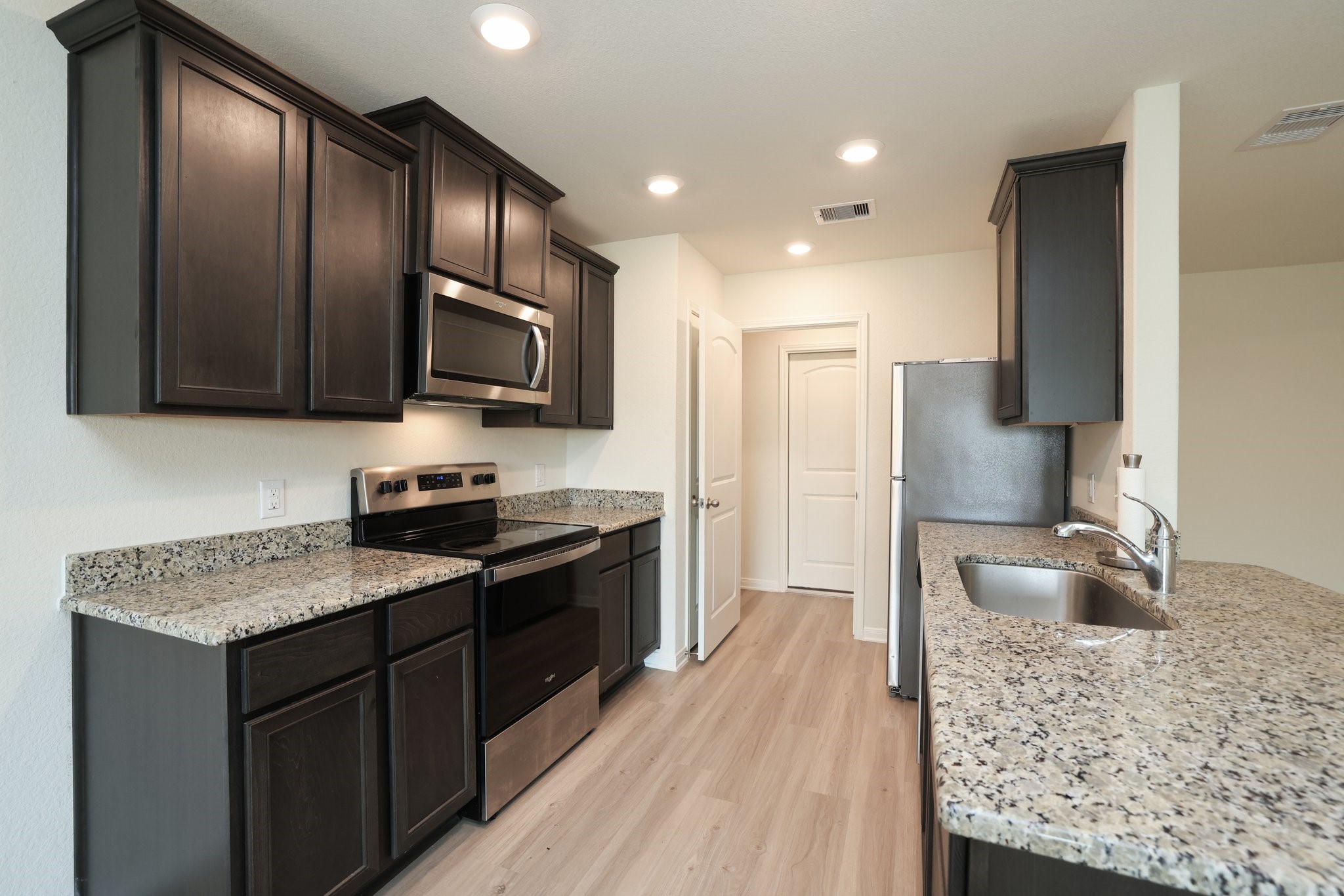 20914 Solstice Point Drive Hockley, TX 77447 - Photo 12 of 27 a kitchen with stainless steel appliances granite countertop wooden cabinets a stove top oven a sink and dishwasher