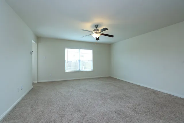 an empty room with a window and a fan