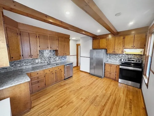 a kitchen with stainless steel appliances kitchen island granite countertop a stove refrigerator and cabinets