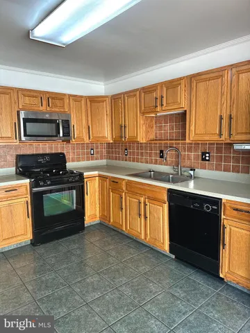 a large kitchen with stainless steel appliances granite countertop a stove a sink and a microwave