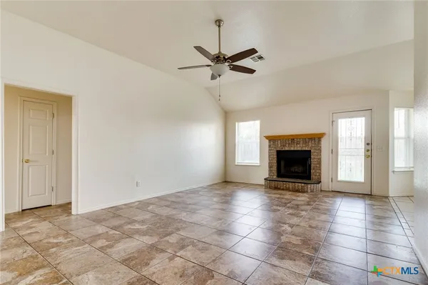 a view of empty room with fireplace and fan