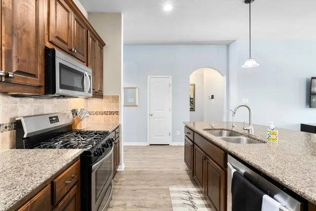a kitchen with stainless steel appliances granite countertop a sink stove and refrigerator