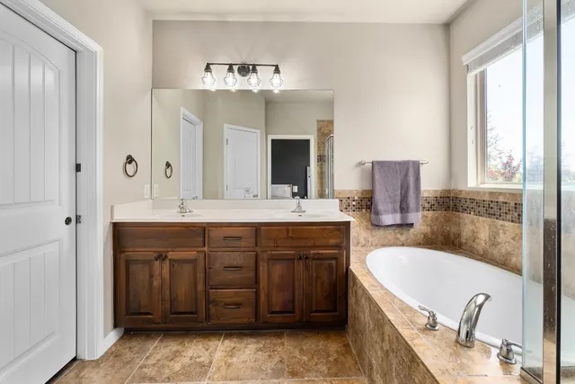 a bathroom with a tub sink double vanity granite and mirror