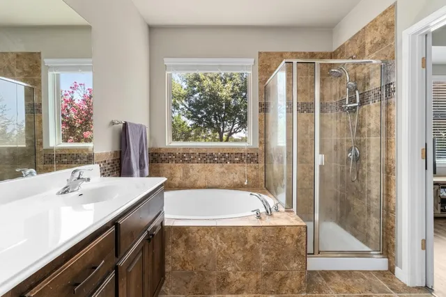 a bathroom with a tub a sink and a large mirror