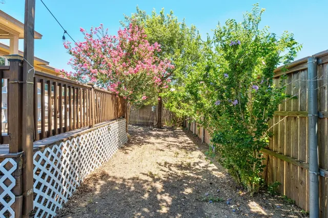 a view of a pathway of a white building with wooden fence