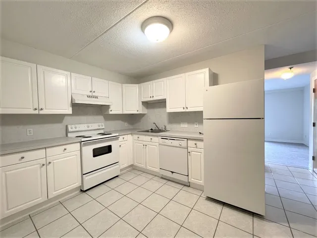 a kitchen with granite countertop white cabinets and white appliances
