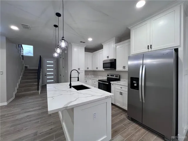 an empty room with wooden floor staircase and windows