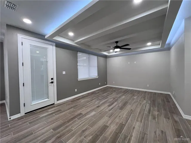 a view of a big room with wooden floor a ceiling fan and windows