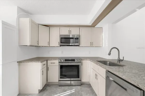 a kitchen with granite countertop white cabinets and stainless steel appliances
