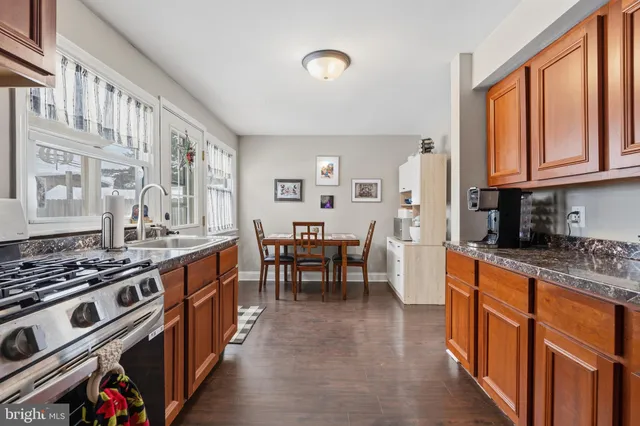 a kitchen with stainless steel appliances granite countertop a stove top oven a sink dishwasher and cabinets with wooden floor