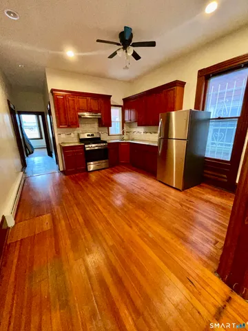 a living room with stainless steel appliances kitchen island granite countertop a stove and a wooden floors