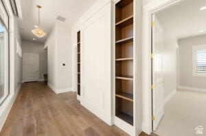 1141 East Lost Ridge Drive Washington, UT 84780 - Photo 104 of 108 Hallway featuring wood-finish flooring, built-in shelving, white paneled walls, and a decorative pendant light fixture