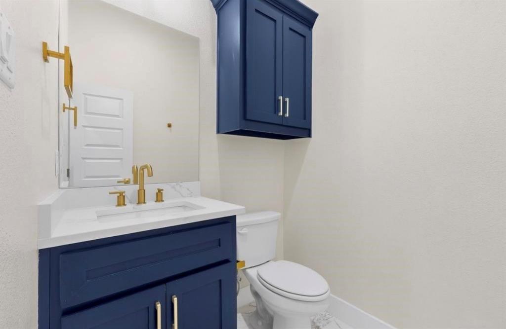 335 Cross Tie Ranch Road Trinidad, TX 75163 - Photo 16 of 30 Bathroom featuring a navy blue vanity with gold hardware, a white countertop, and a matching navy blue wall cabinet