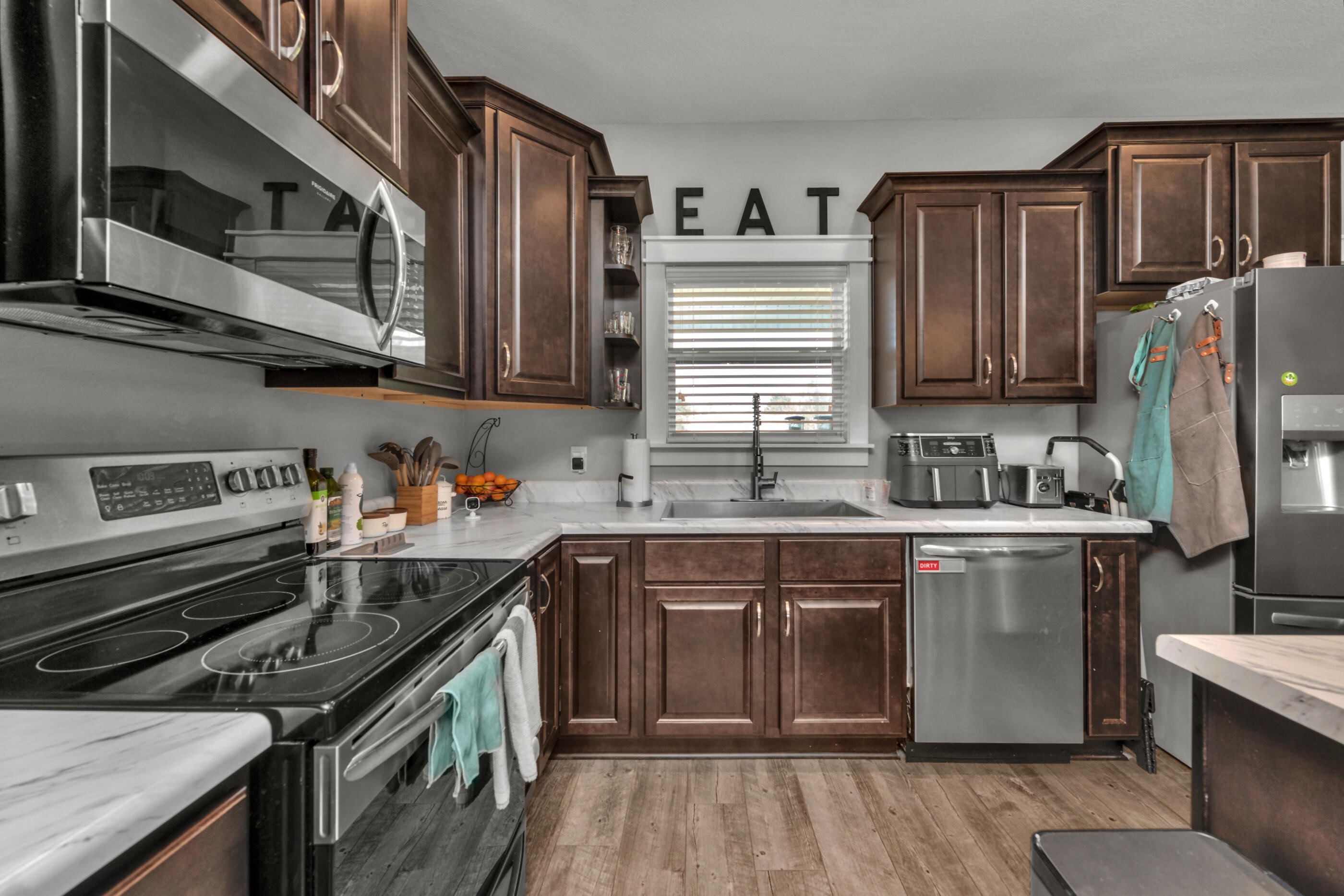 6116 Robin Road Crestview, FL 32539 - Photo 8 of 24 a kitchen with stainless steel appliances granite countertop a stove a sink dishwasher and a microwave oven with wooden cabinets
