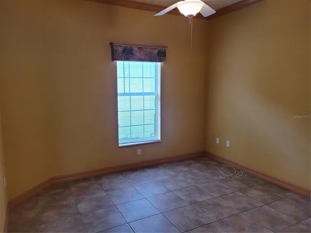 an empty room with windows and chandelier fan