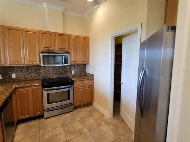 a kitchen with granite countertop a refrigerator and a stove top oven