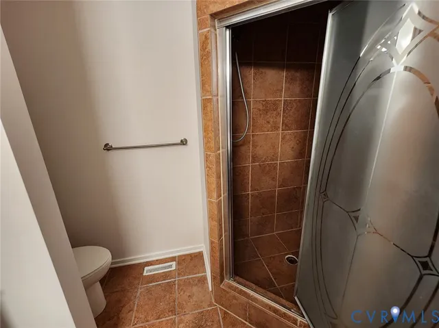 a bathroom with a glass door shower and a toilet