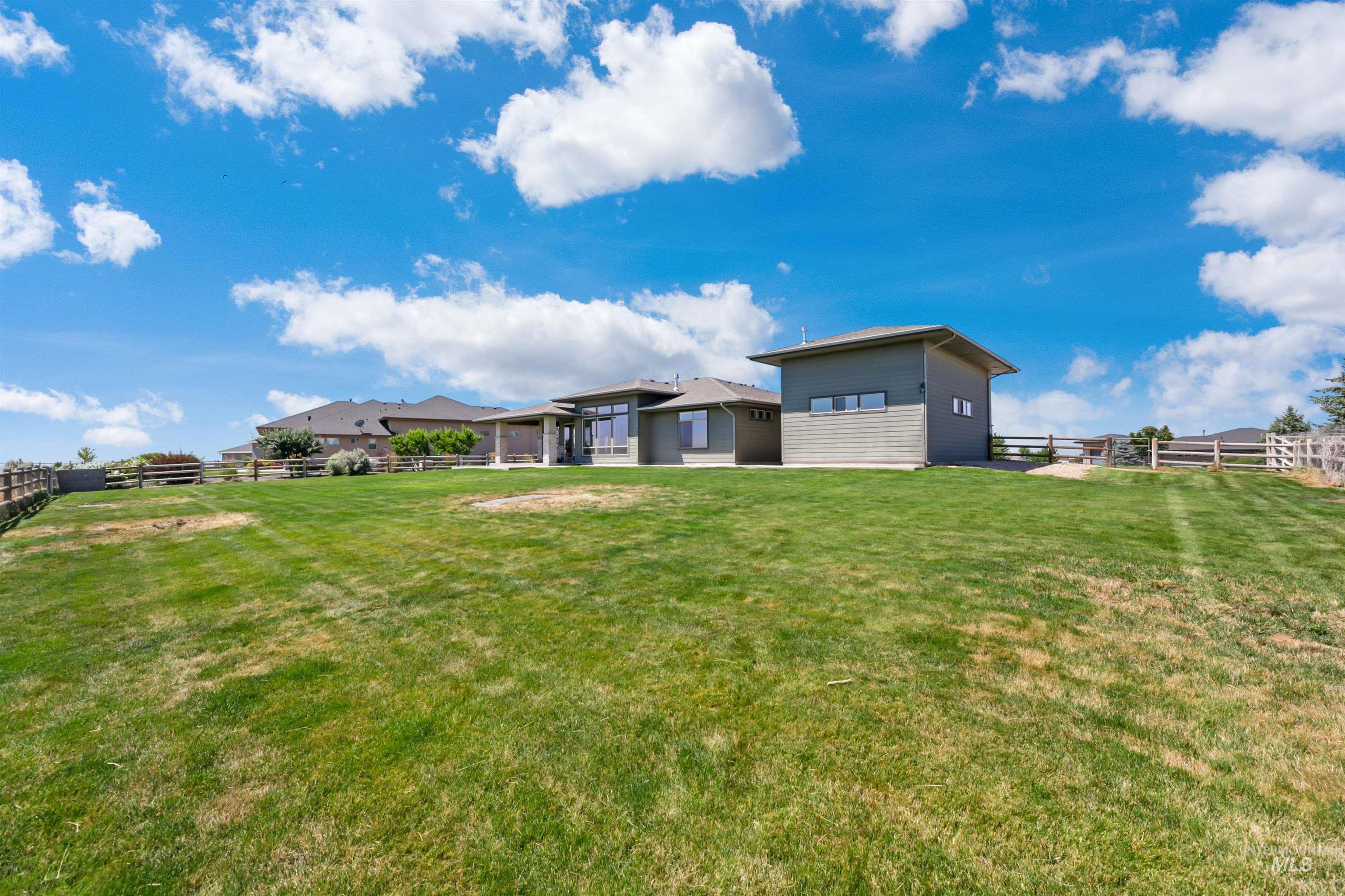 24398 Tombstone Ridge Court Middleton, ID 83644 - Photo 45 of 47 Spacious rear yard with a split-rail fence and a detached accessory structure featuring horizontal siding and multiple windows