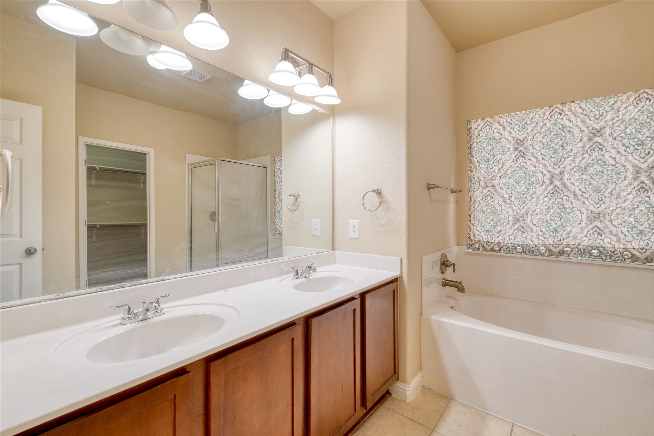 194 Cold Springs Spring Buda, TX 78610 - Photo 11 of 17 Full bathroom with double vanity, a garden tub, light tile patterned floors, a shower stall, and a walk in closet
