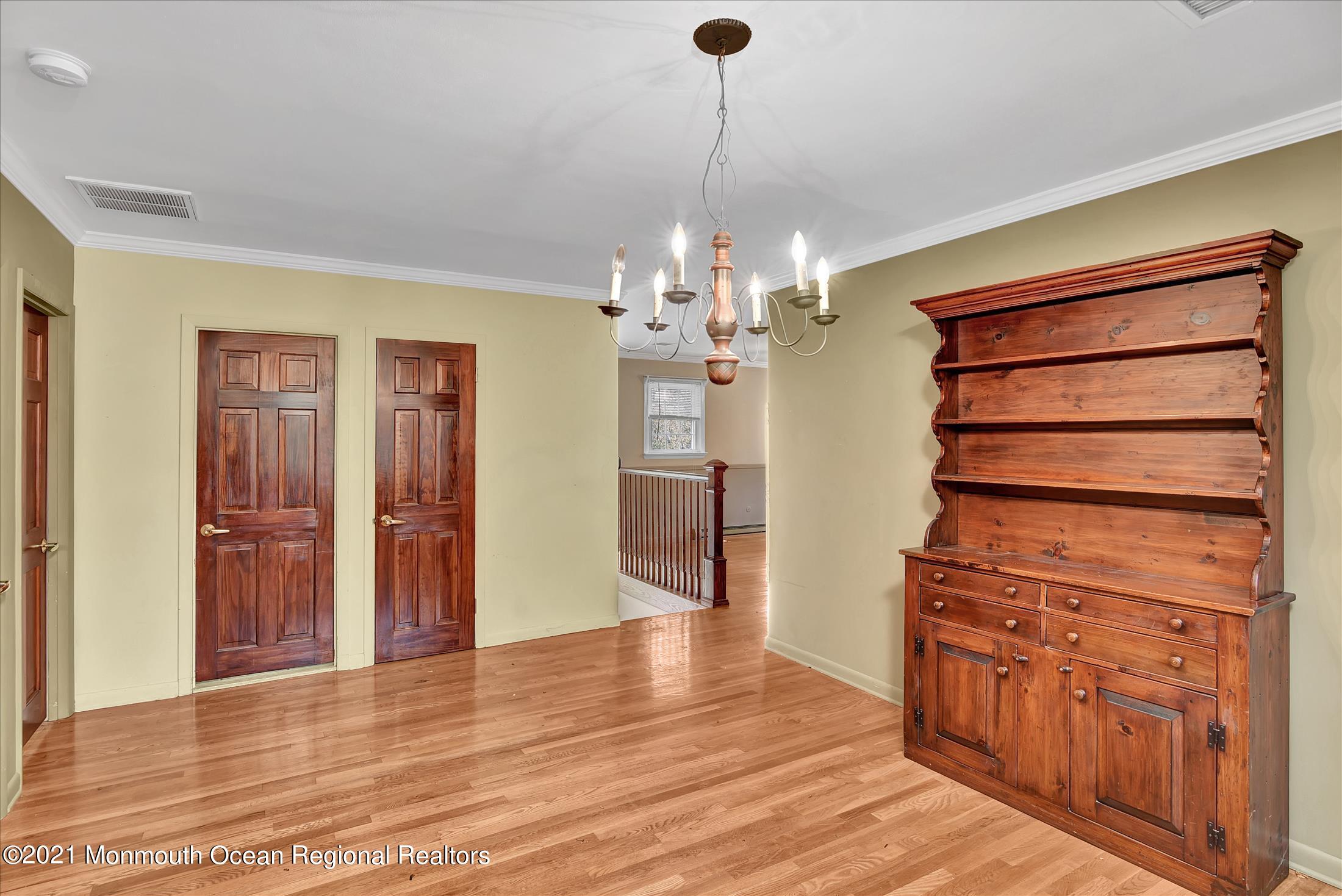 149 Crine Road Morganville, NJ 07751 - Photo 18 of 28 a view of a hallway with wooden floor and chandelier