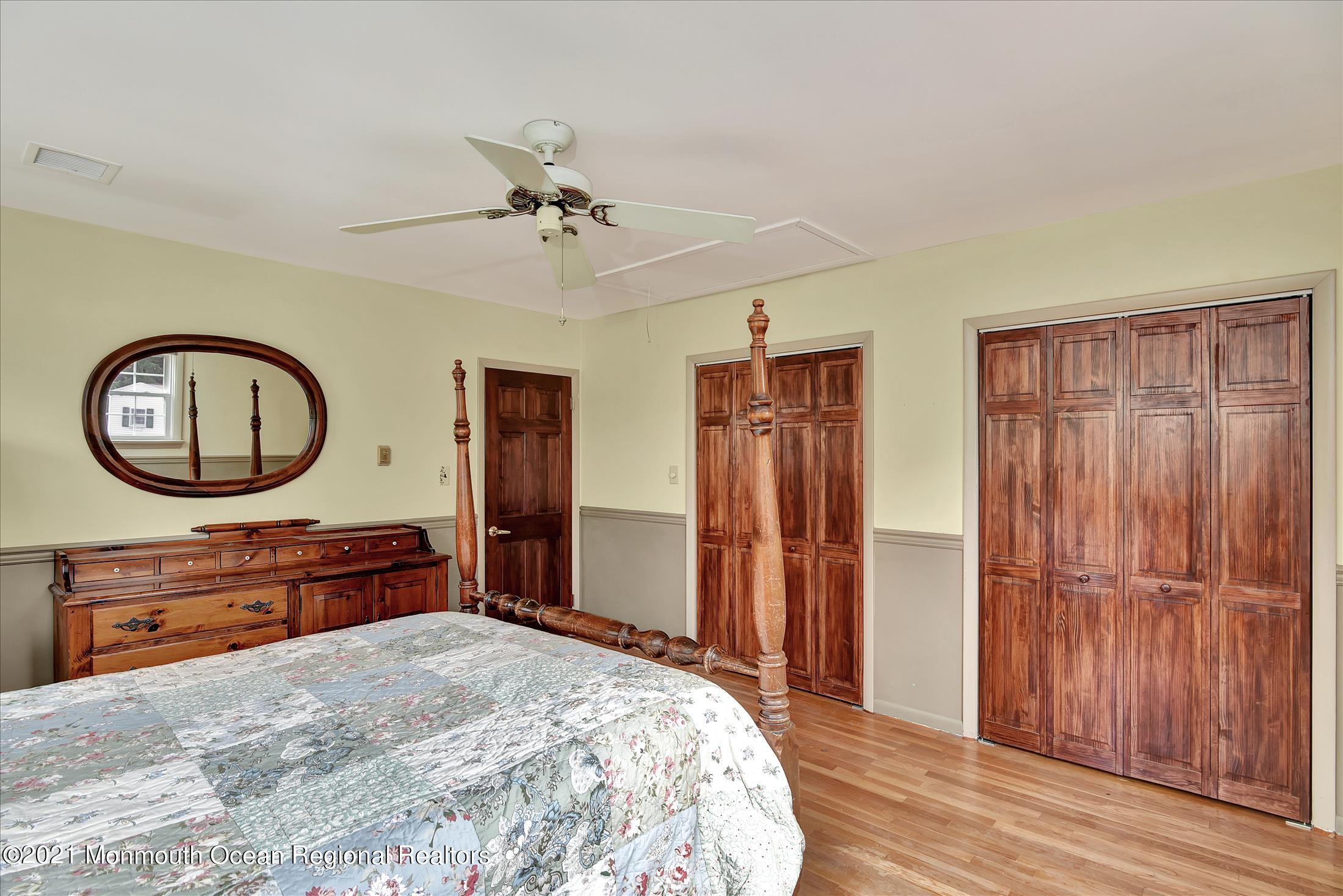 149 Crine Road Morganville, NJ 07751 - Photo 24 of 28 a bedroom with a bed a mirror on dresser and a chandelier