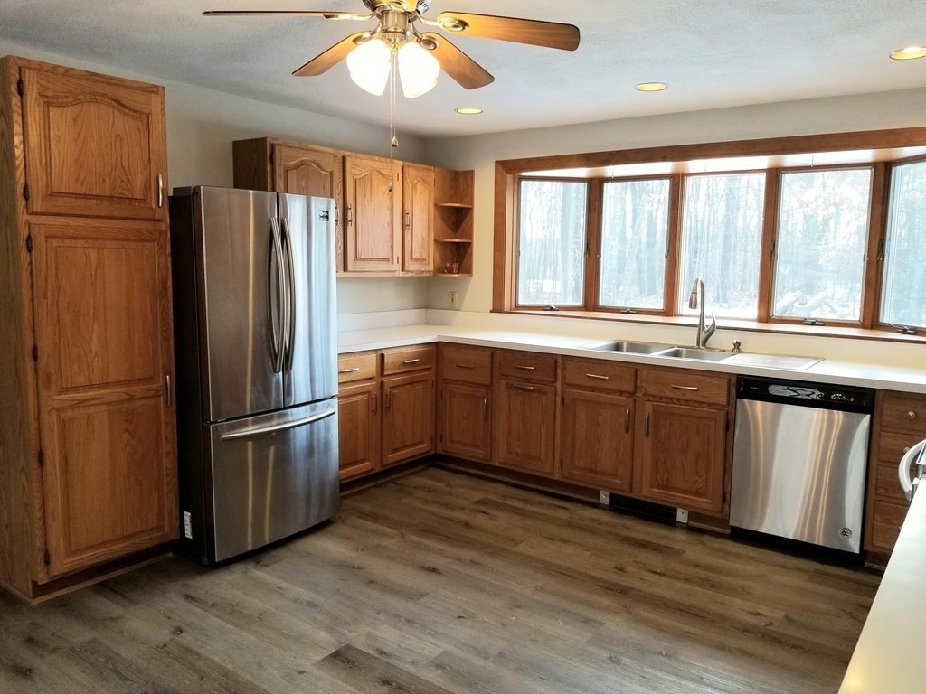 22 Whitney Road Shirley, MA 01464 - Photo 5 of 42 a kitchen with stainless steel appliances granite countertop a refrigerator a sink a stove and white cabinets with wooden floors