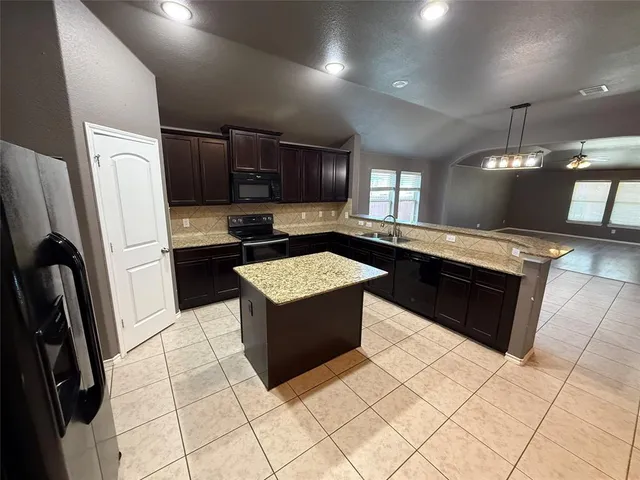 a kitchen with stainless steel appliances granite countertop a stove a sink and a refrigerator