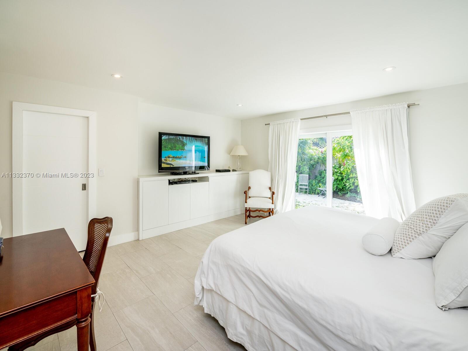 280 Hampton Lane Key Biscayne, FL 33149 - Photo 20 of 30 a bedroom with a bed a chair and a flat screen television