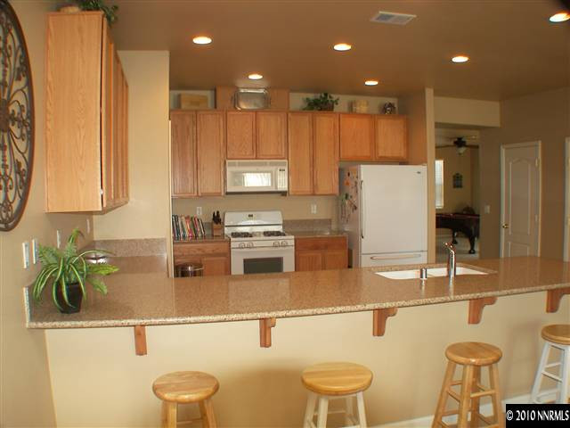 10799 Stone Hollow Drive Reno, NV 89521 - Photo 3 of 9 a kitchen with a sink a stove and chairs