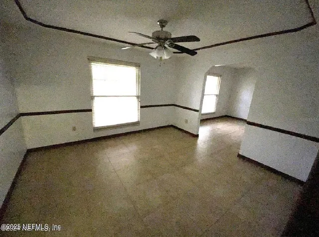 an empty room with windows and fan