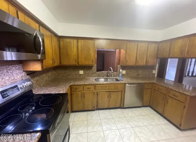 a kitchen with granite countertop a stove a sink and a microwave