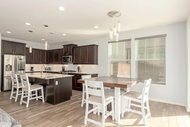 a kitchen with stainless steel appliances kitchen island granite countertop a stove a refrigerator a kitchen island with a dining table and chairs